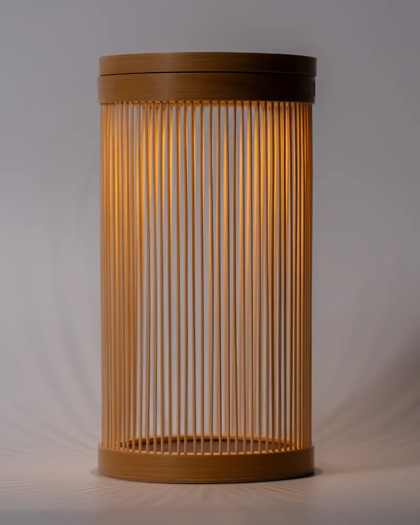 The Bamboo Lantern glowing against a grey background, warm light falling through the fine bamboo strips
